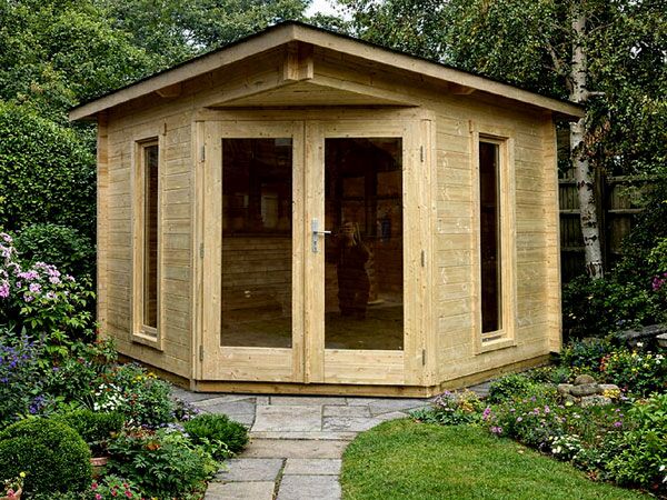 A corner log cabin with double doors and large windows on either side, made of interlocking logs.