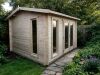An apex log cabin with large windows and a sloping roof