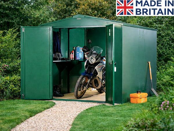 A green metal shed with a motorcycle stored inside. The shed has a workbench and tools.