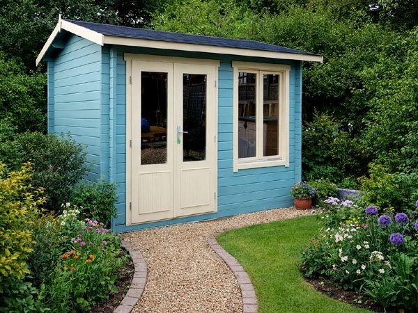 A blue painted log cabin with white trim and a dark roof. The cabin has double doors and a window.