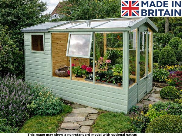 Graffham Greenhouse Shed 1 A small green garden potting shed with glass panels and plants inside. The shed has a light green exterior with a glass roof and walls.